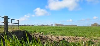 Blauw bewolkte lucht en zon boven de Groninger landerijen 