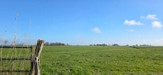 Blauw bewolkte lucht en zon boven de Groninger landerijen 