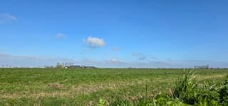 Blauw bewolkte lucht en zon boven de Groninger landerijen 