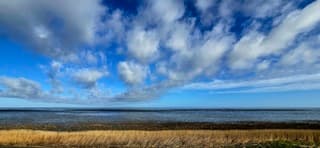 Wolkenluchten boven het wad