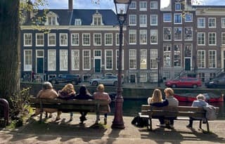 Jong en oud op een bankje genietend van de zon in het centrum van Amsterdam