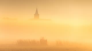 Prachtige laag mist met daarboven de kerktoren van Anjum 