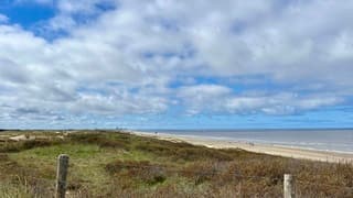 Zicht op zee en  strand, met aan de horizon Scheveningen en Den Haag 