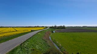 Contrast blauw lucht, koolzaad en rook zichtbaar in de kop van nh