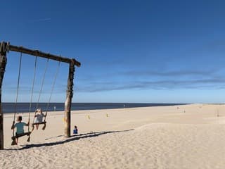 Rook bosbrand Veluwe aan noordzeekust met schommelende kinderen op het strand 