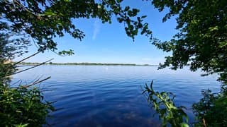 Doorkijkje naar strakblauwe lucht langs het water
