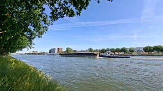 V-vorm door de helling kanaal en bomen, vrachtschip vaart door Amsterdam Rijnkanaal bij volop zon en wat lichte bewolking
