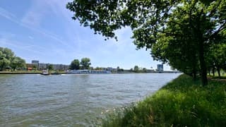  V-vorm door de helling kanaal en bomen, grote rondvaart boot is aan het aanmeren bij Amsterdam Rijnkanaal bij volop zon