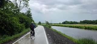 Fietser in een regenbui in de provincie Groningen vanmiddag 