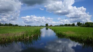 Zon, stapelwolken en een schitterende reflectie van de wolken in het water