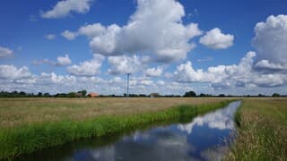 Stapelwolken en zon in een fraai polderlandschap einde ochtend