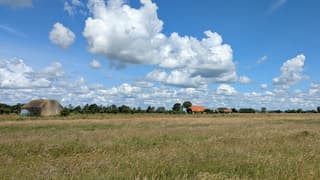 Schitterende stapelwolkenluchten en zon in polderlandschap 
